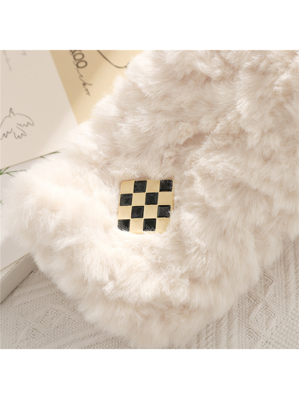 Close-up of the black-and-gold checker accent on a white fuzzy scarf