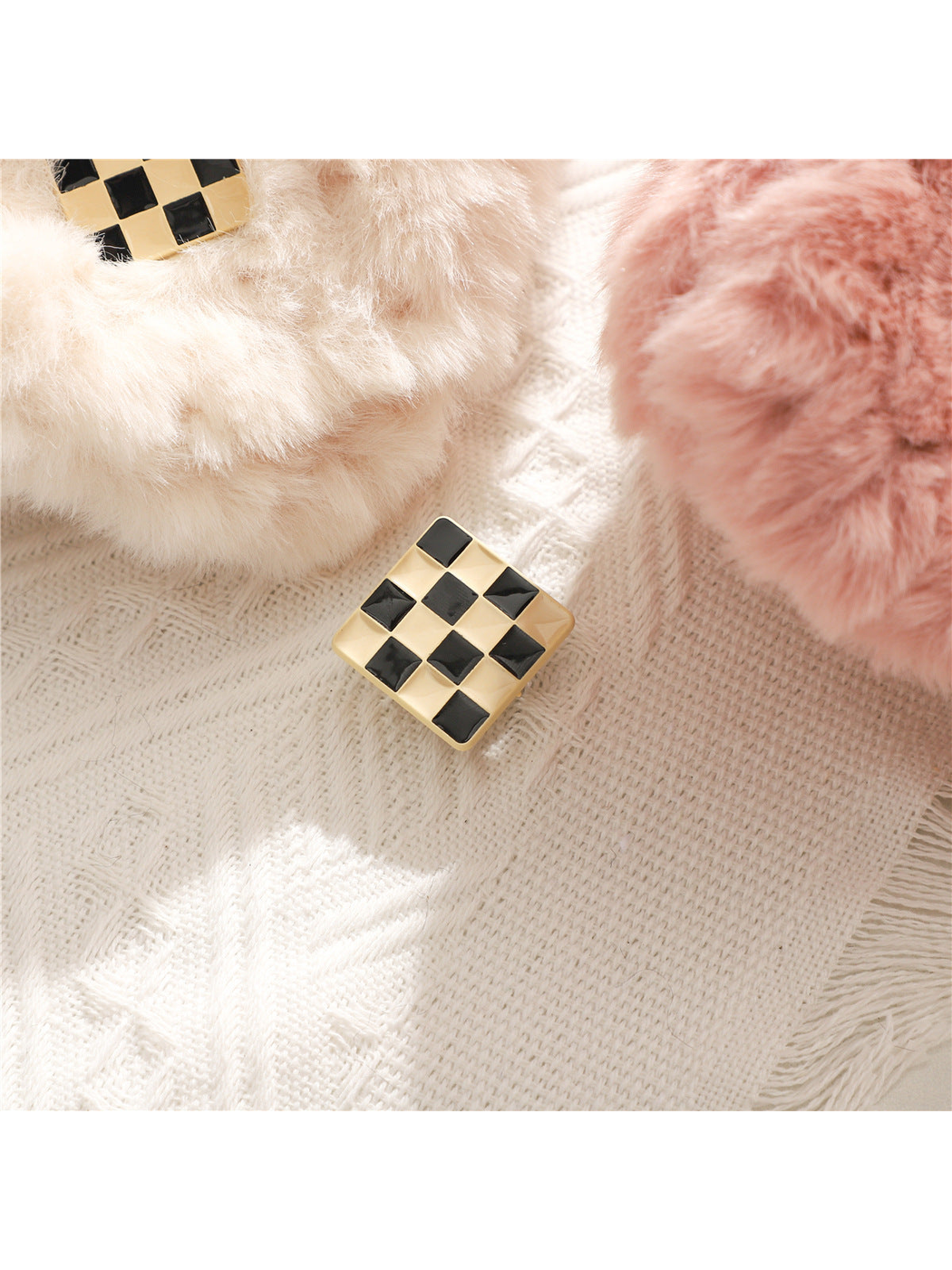 Black-and-gold checker square accent beside white and pink fuzzy scarf ends