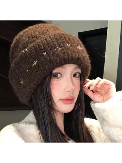Brown fuzzy ribbed beanie with contrasting stitched motifs, worn view