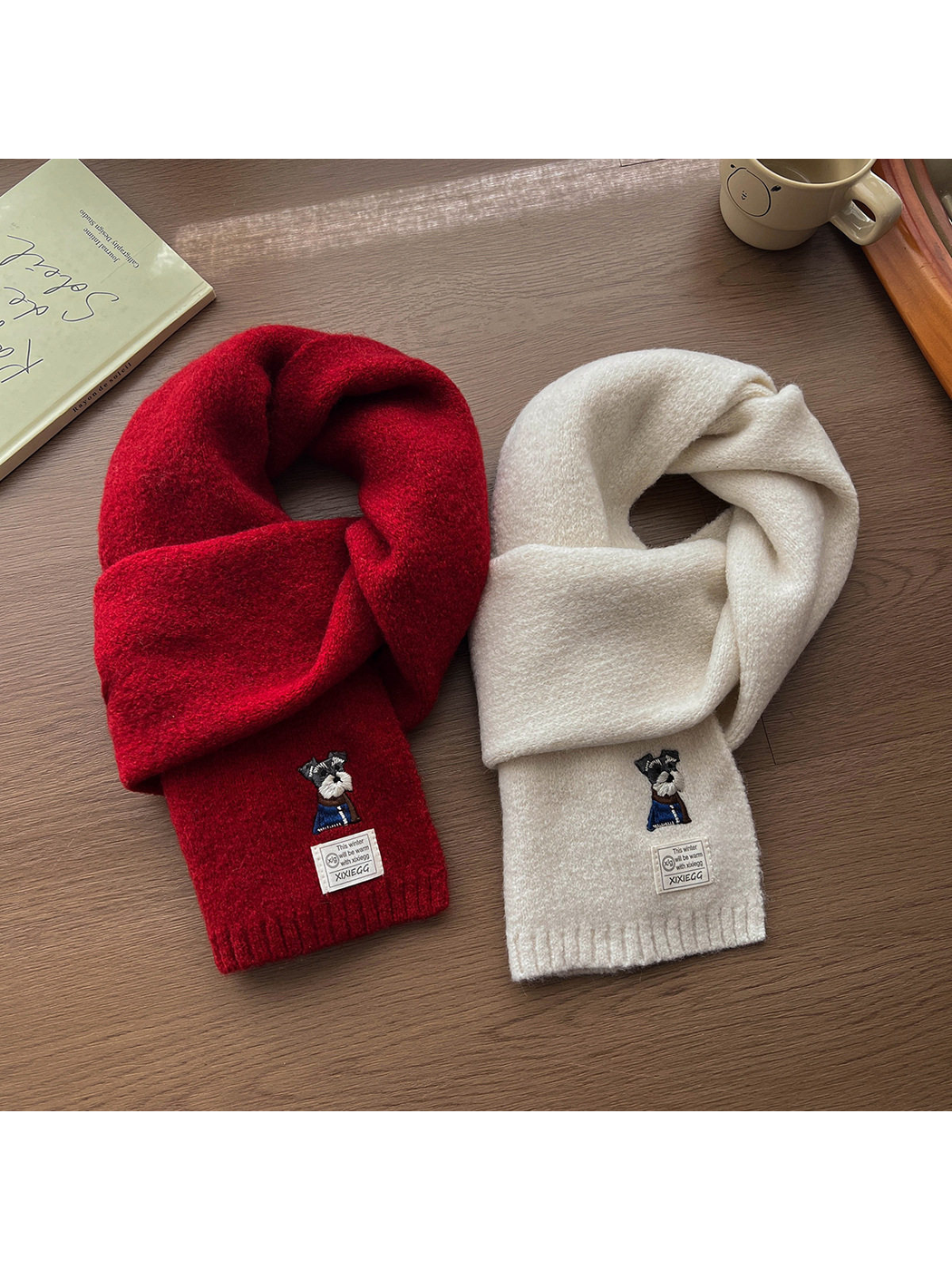 Red and ivory scarves arranged side by side to show their knotted shape and embroidered motifs