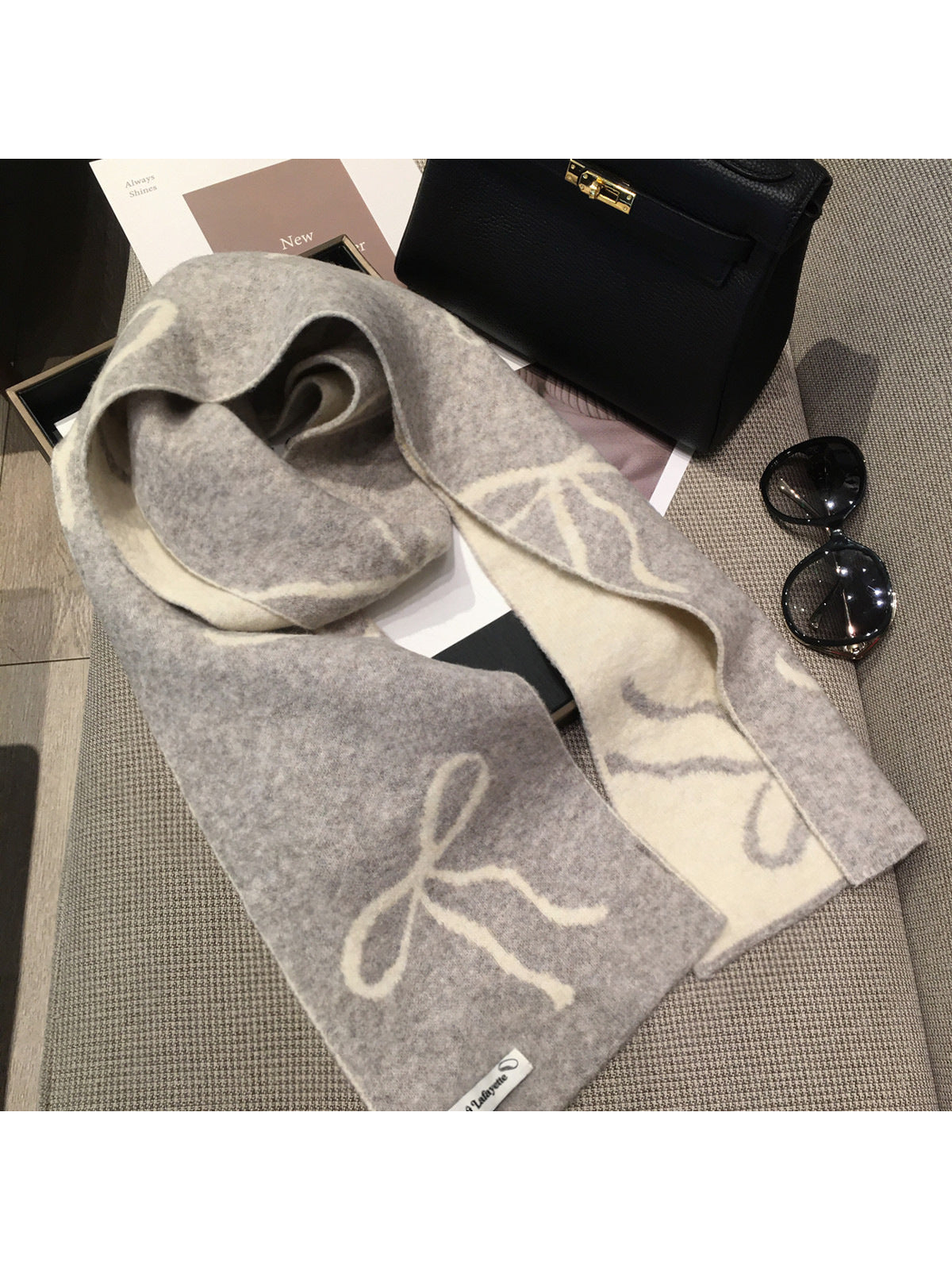 Gray bow-pattern scarf draped to reveal its contrasting cream reverse