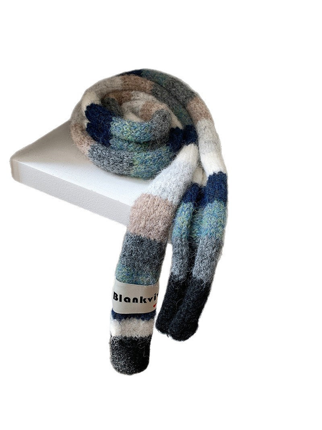 Navy, gray and beige fuzzy color-block scarf coiled and draped on a white shelf