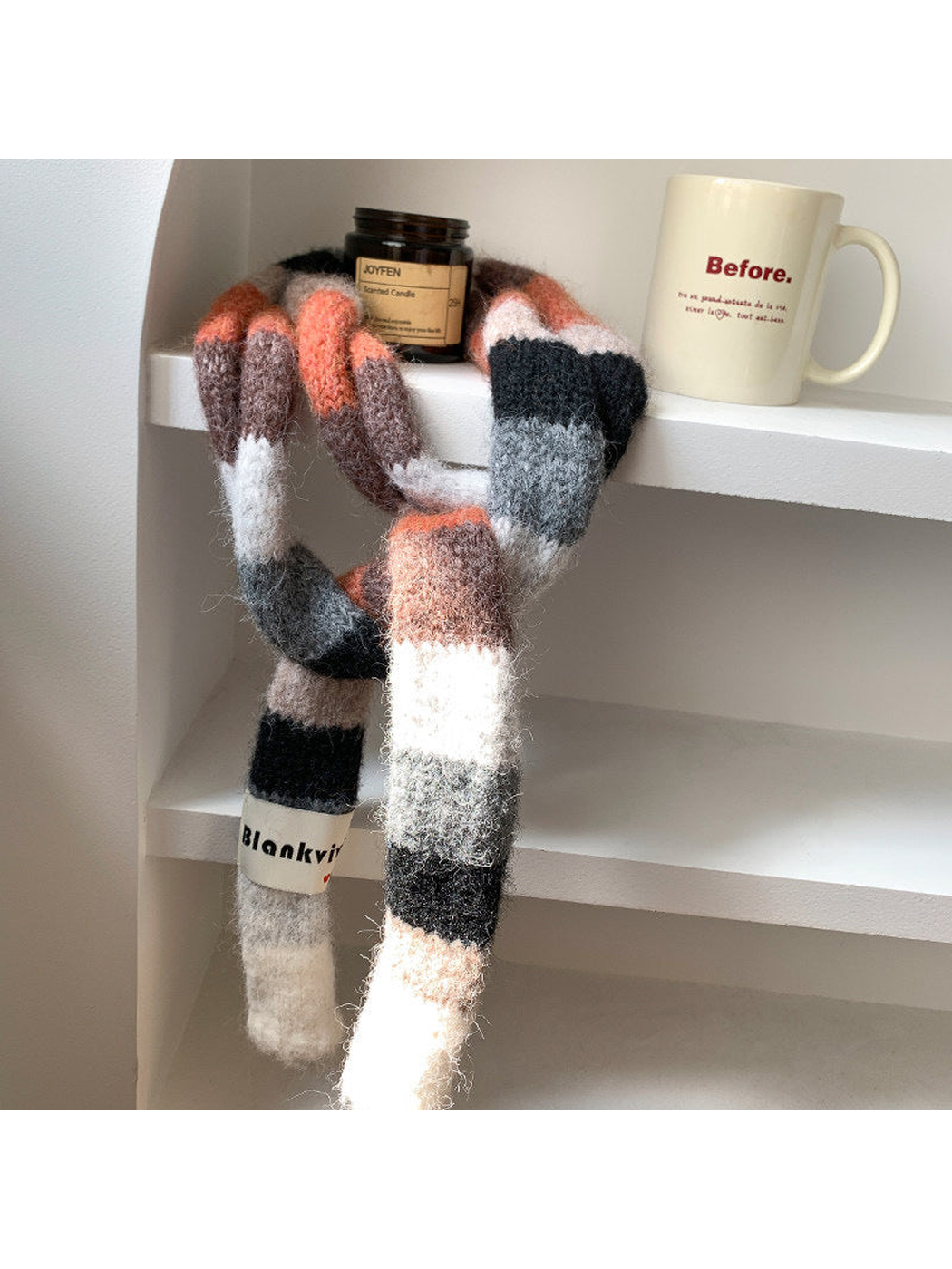 Black, gray, white and coral fuzzy color-block scarf draped over a shelf