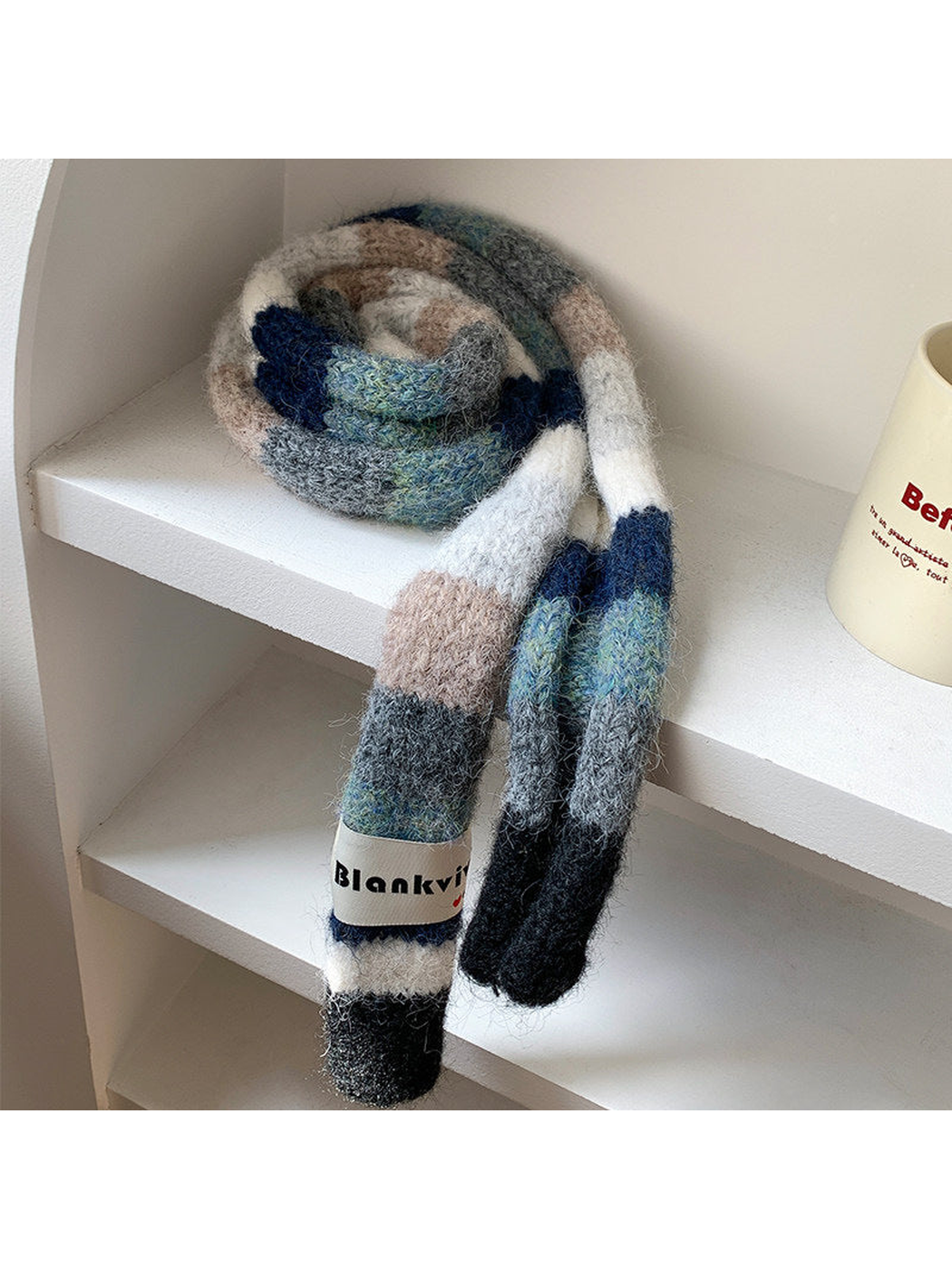 Navy, gray and beige fuzzy color-block scarf coiled and draped on a shelf