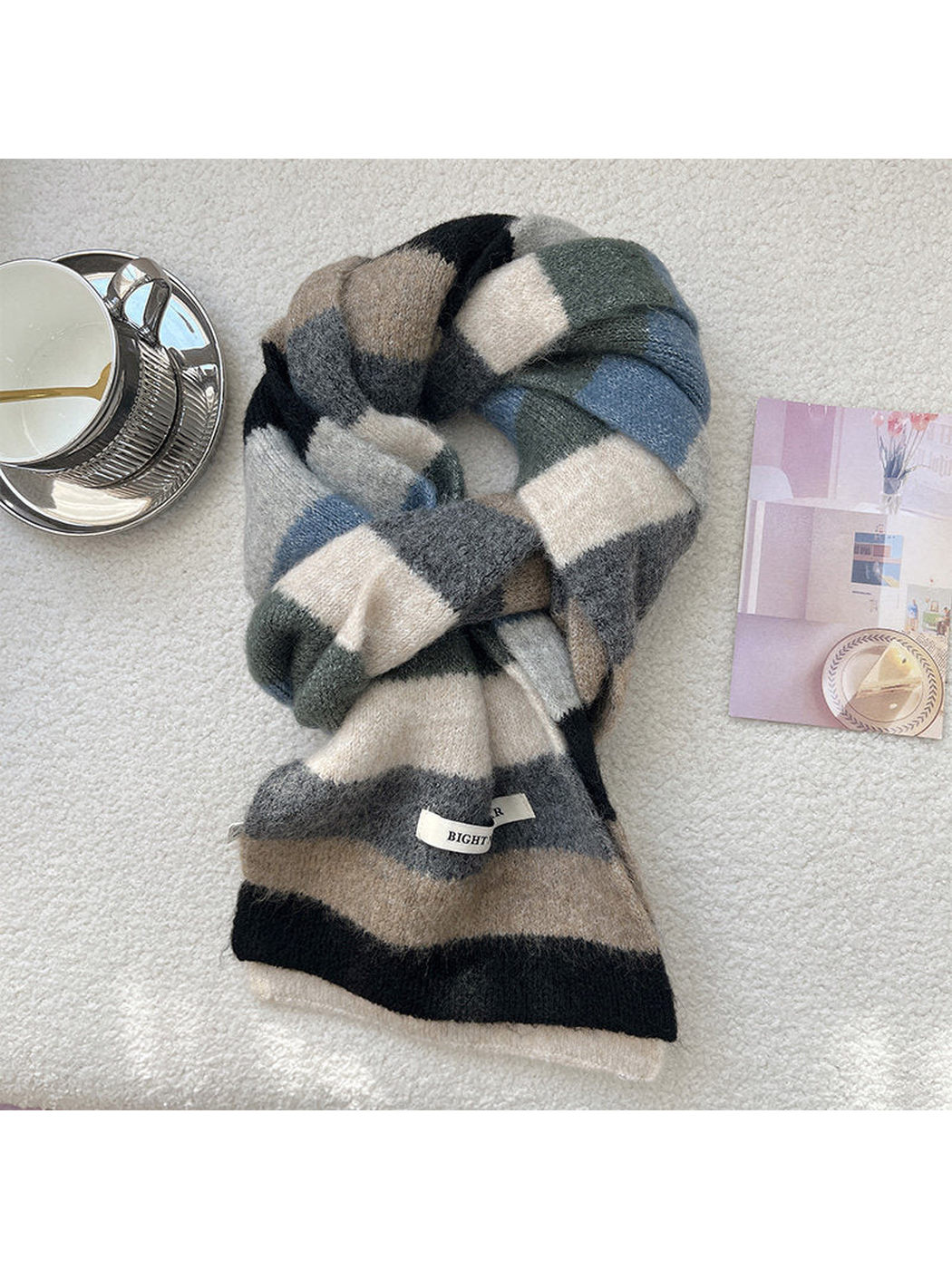 Black, gray, beige, ivory and muted blue striped scarf arranged in a loose knot