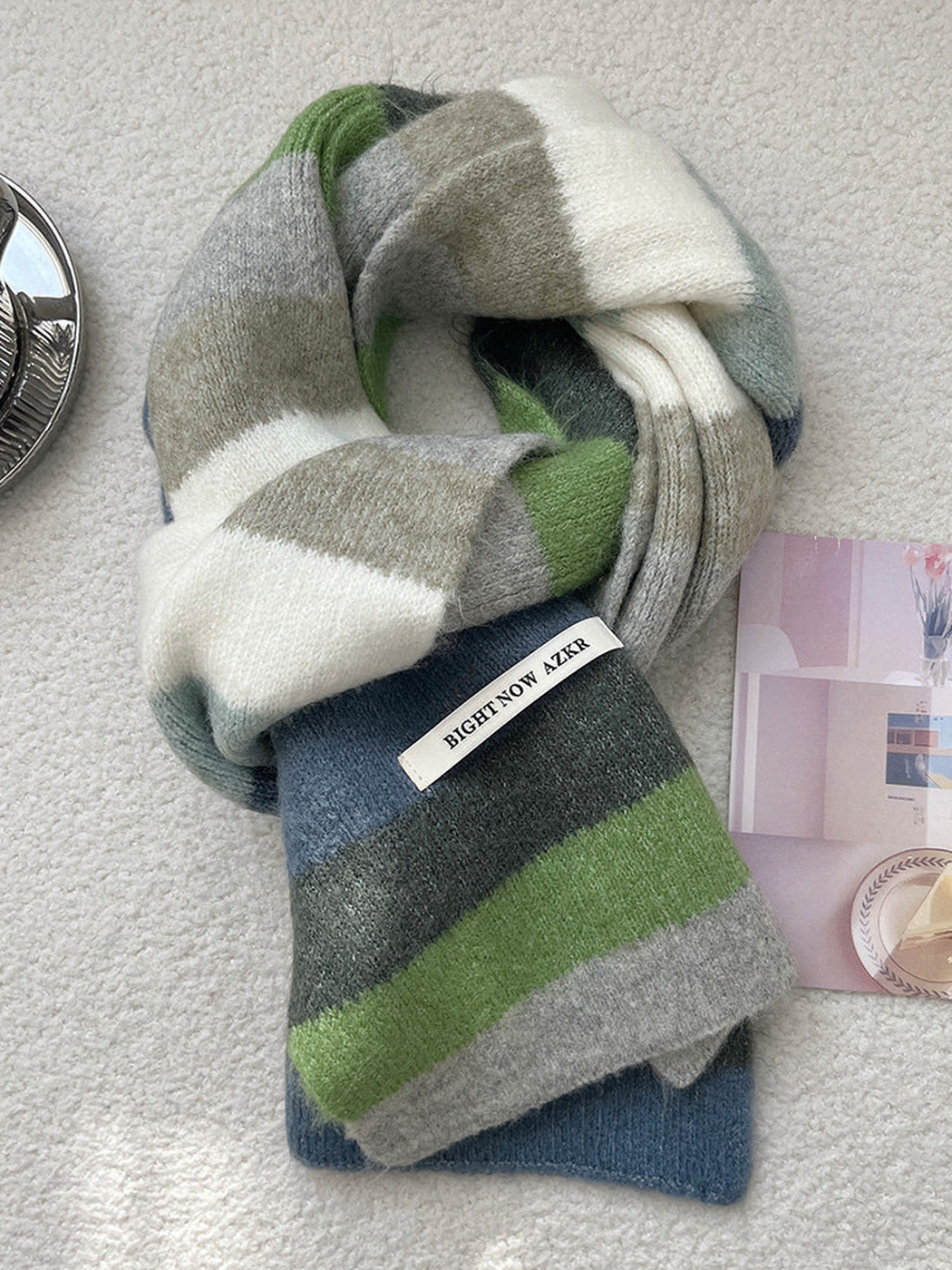 Blue-gray, charcoal, green, light gray and ivory striped scarf arranged in a loose knot