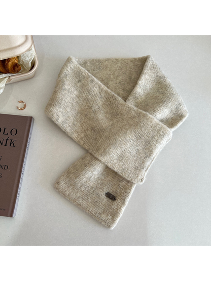 Ivory narrow scarf arranged in a crossed loop with a metal-tone end plaque