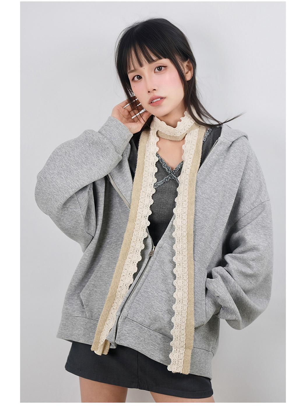 Beige narrow scarf with scalloped lace trim worn in a long draped style