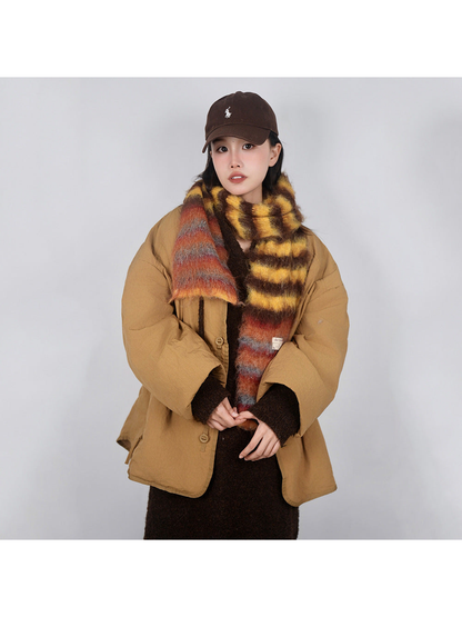 Yellow, brown and orange striped fuzzy scarf styled over a tan coat