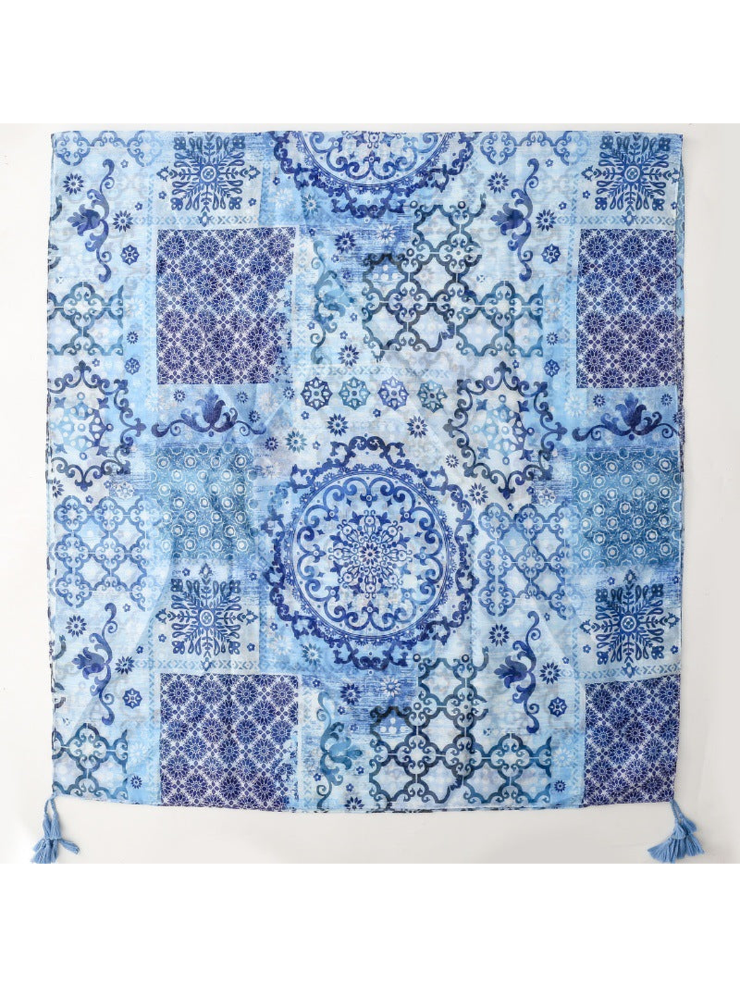 Blue patchwork-pattern scarf laid flat with corner tassels