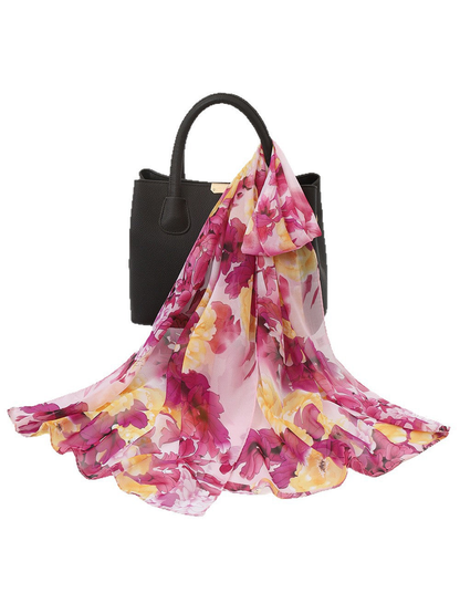 Pink and yellow floral scarf draped over a black handbag