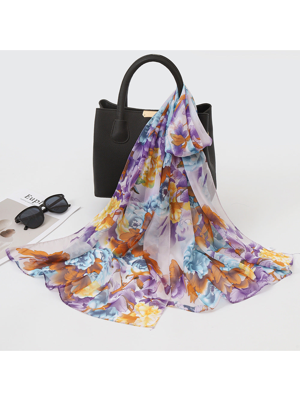 Purple, blue and orange floral scarf draped over a black handbag