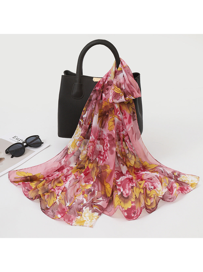 Blush pink and golden floral scarf draped over a black handbag