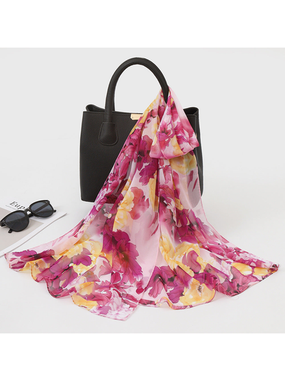 Pink and yellow floral scarf draped over a black handbag