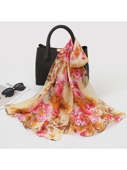 Khaki, pink and brown floral scarf draped over a black handbag