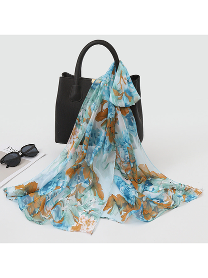 Light blue and brown floral scarf draped over a black handbag