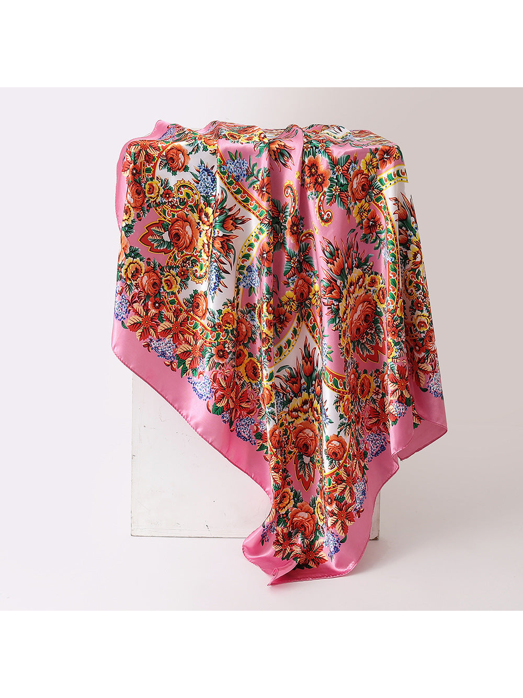 Pink square scarf with orange-red floral and paisley print, draped view