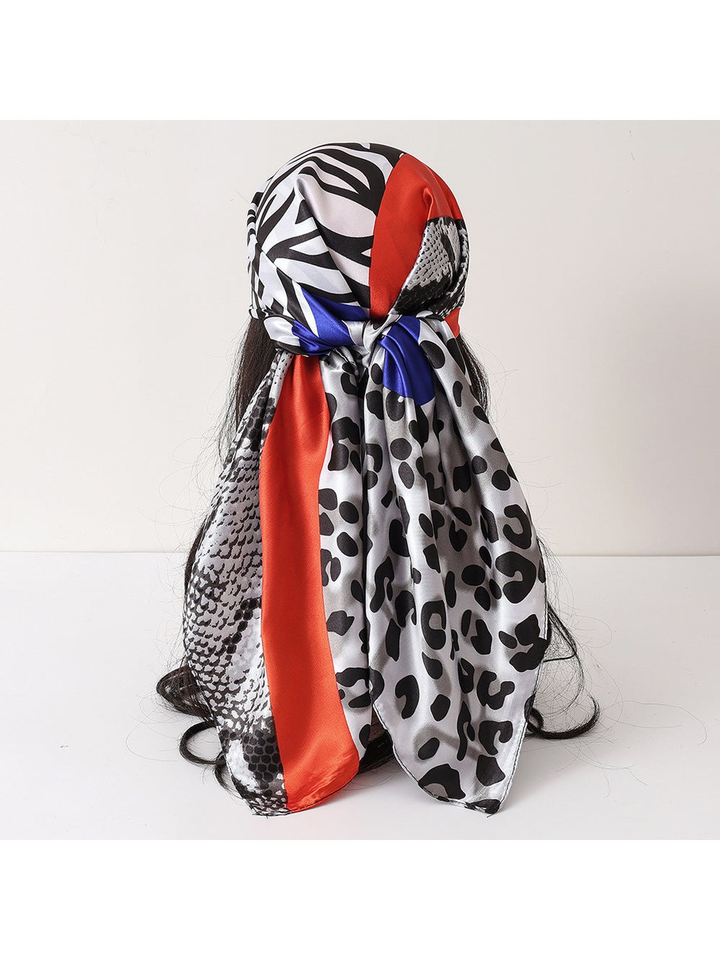 Gray animal-print scarf tied around a mannequin head with red and blue accents