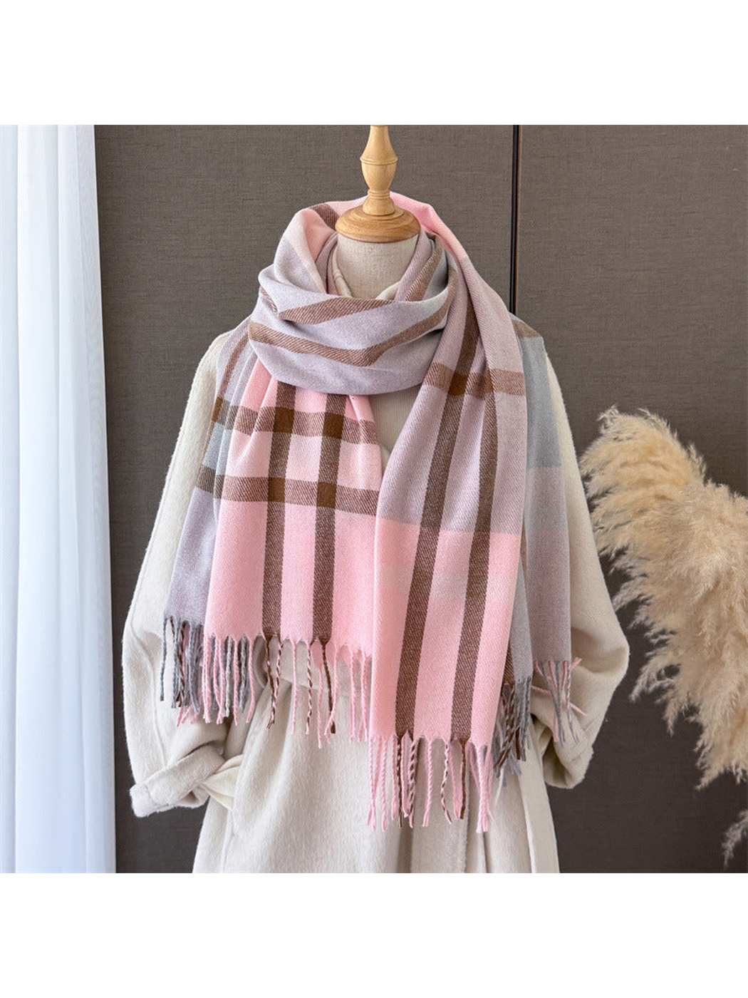 Pink and gray plaid scarf wrapped on a mannequin with fringed ends draped in front