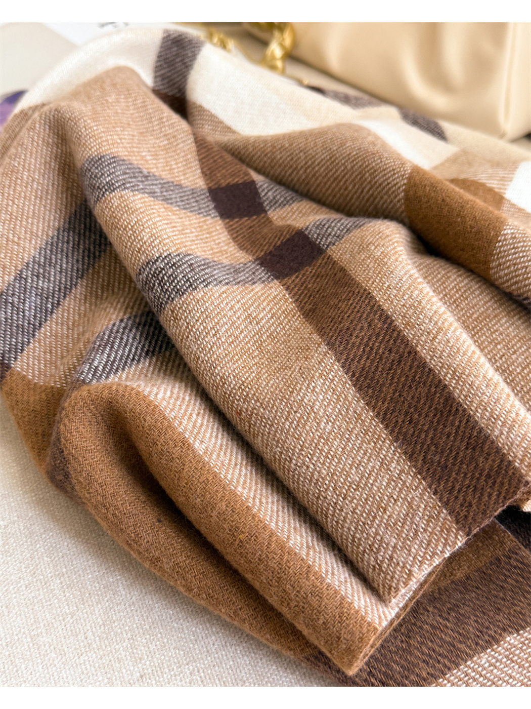 Close-up of the brown plaid scarf folded to show its woven texture and color bands