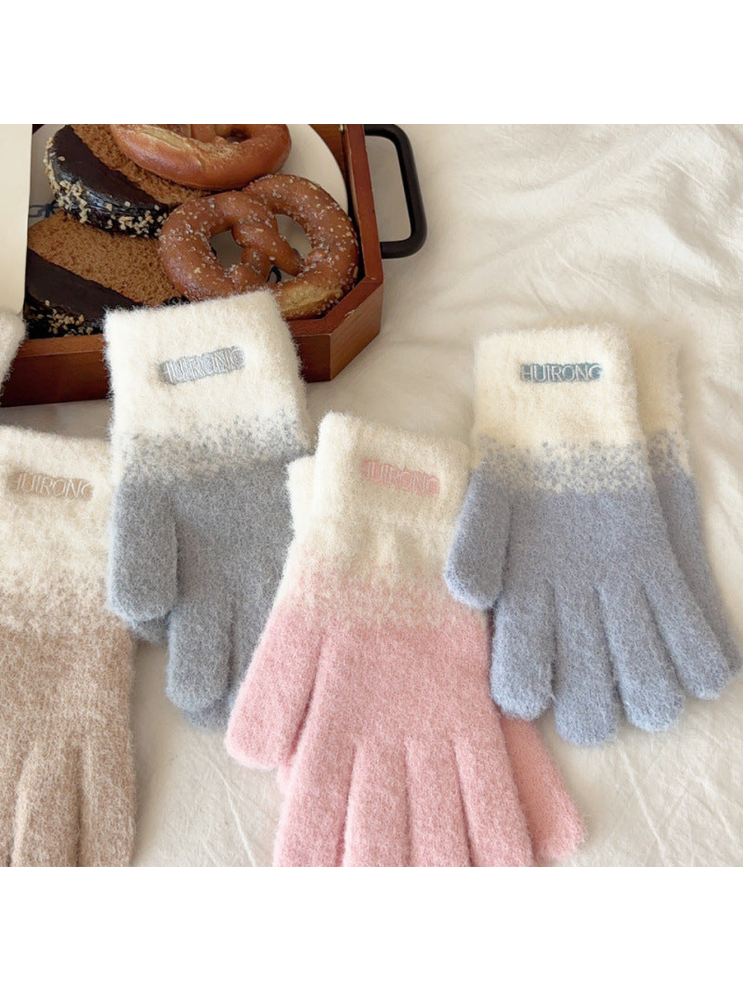 Pink, gray, blue and beige gloves displayed in a styled flat lay