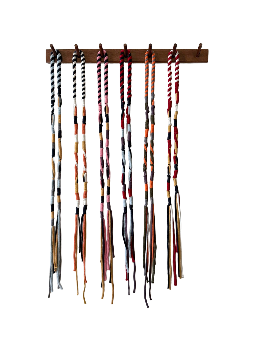 Six multicolor skinny scarf variants hanging in a row