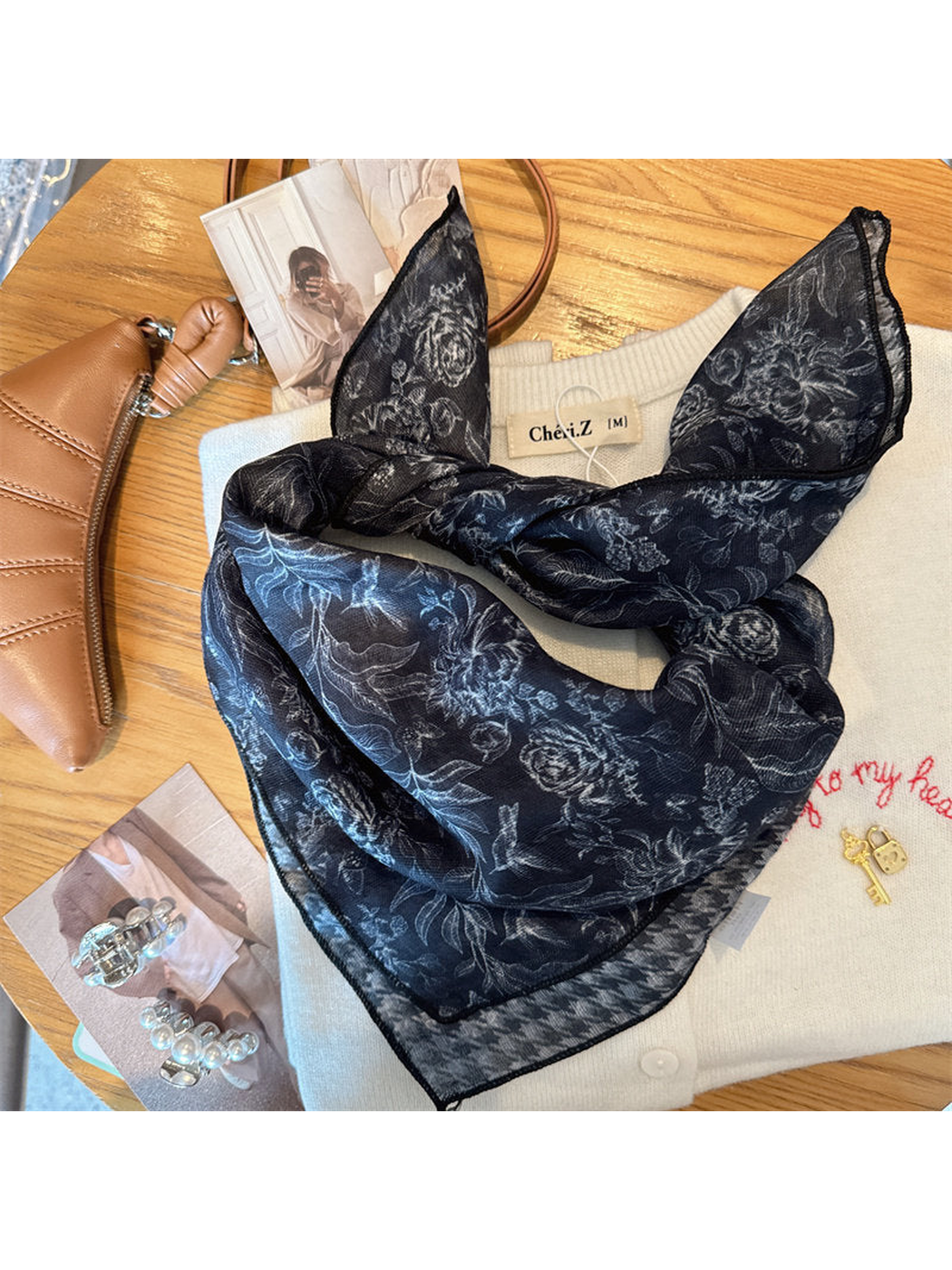Navy floral scarf loosely tied over a cream cardigan