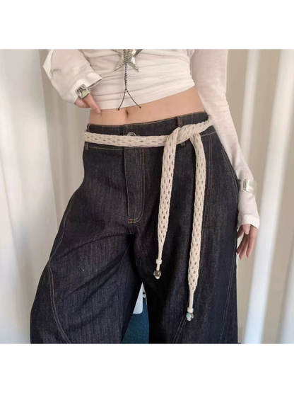 Beige openwork scarf tied at the waist over dark wide-leg jeans