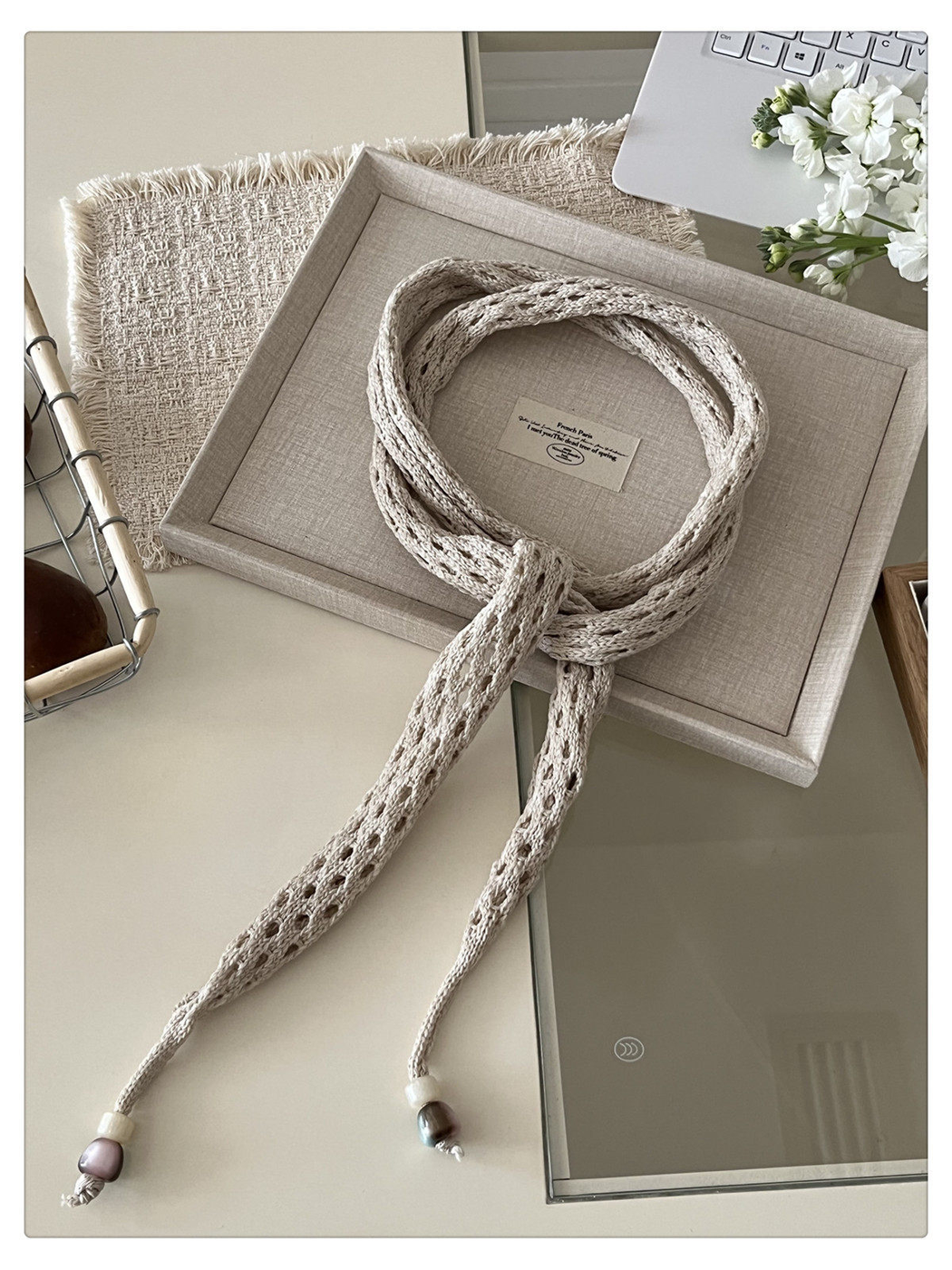 Beige openwork scarf arranged in a loose neck-style knot