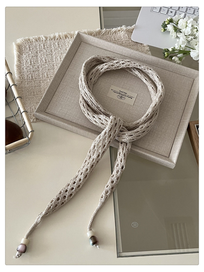 Beige openwork scarf arranged in a loose neck-style knot
