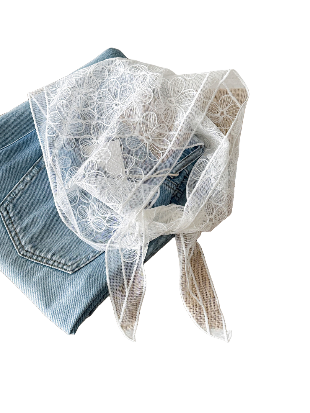 White sheer floral scarf arranged over denim to show the embroidered flower pattern