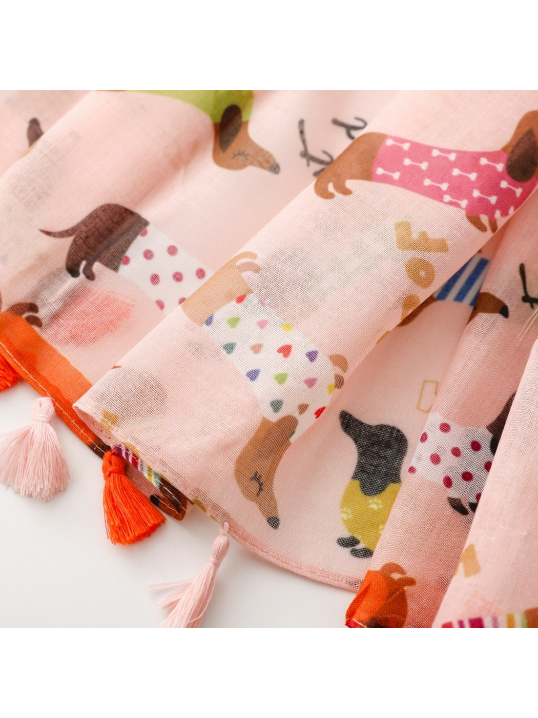 Close-up of alternating orange and pale pink tassels along the scarf edge