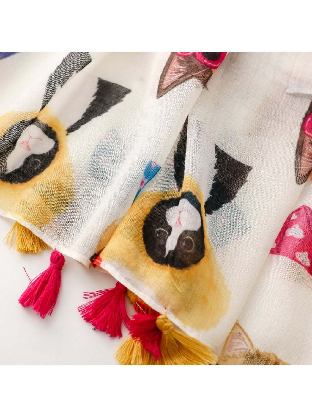 Close-up of pink and mustard tassels along the cat-print scarf edge