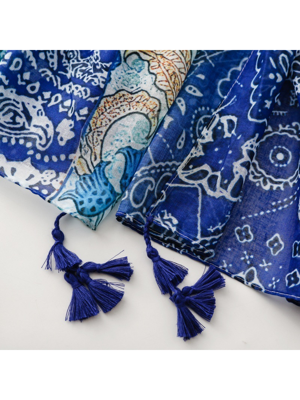 Close-up of dark blue tassel clusters beside the scarf's printed hem