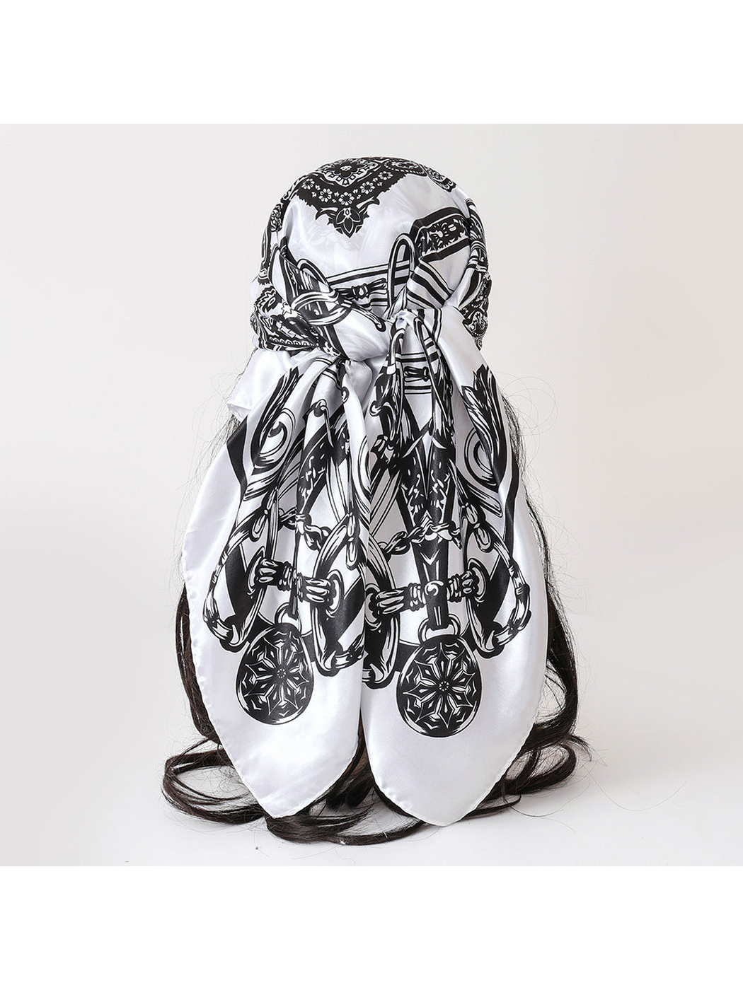 Black and white patterned square scarf tied over a display form