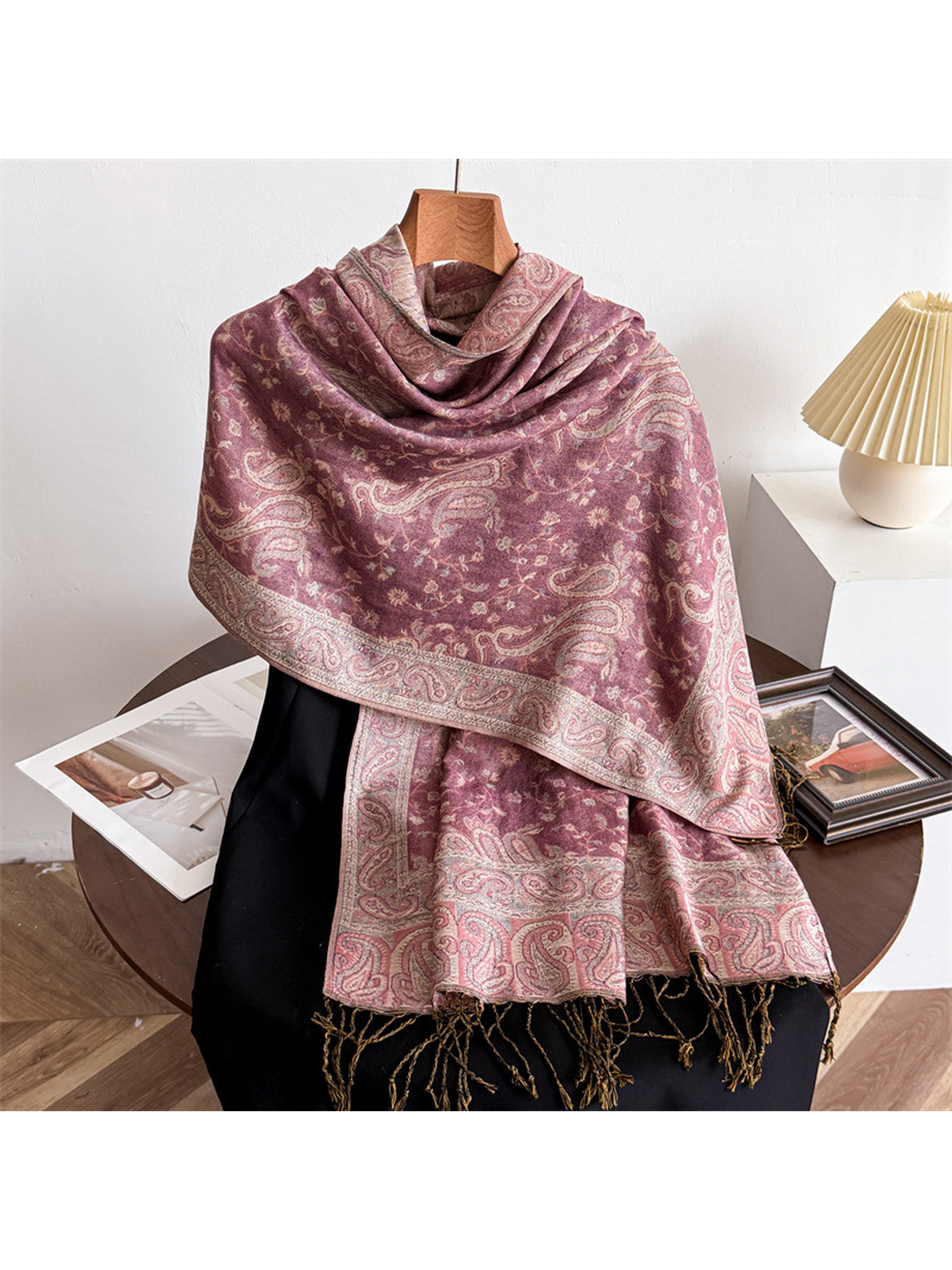 Dusty pink paisley scarf draped on a display form with fringed ends