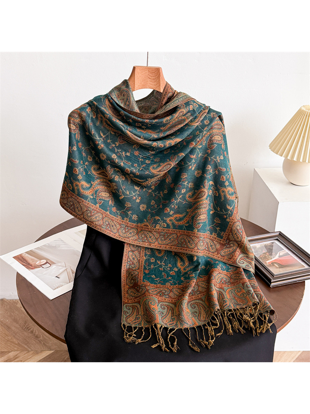 Deep teal paisley scarf draped on a display form with fringed ends