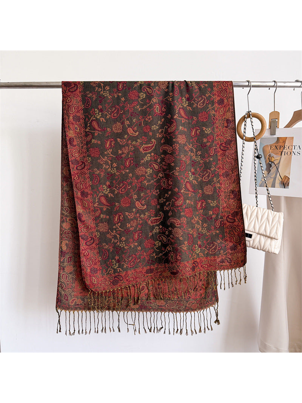 Dark brown paisley scarf displayed flat with a red ornamental border and fringe