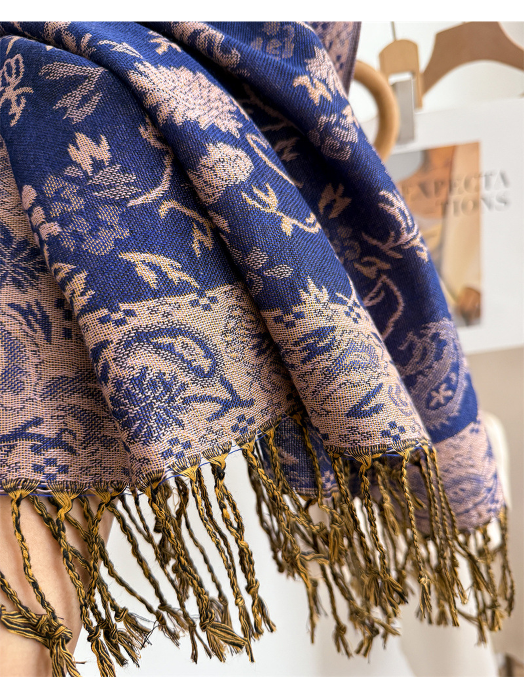 Close-up of the woven paisley border and twisted fringe on the royal blue scarf