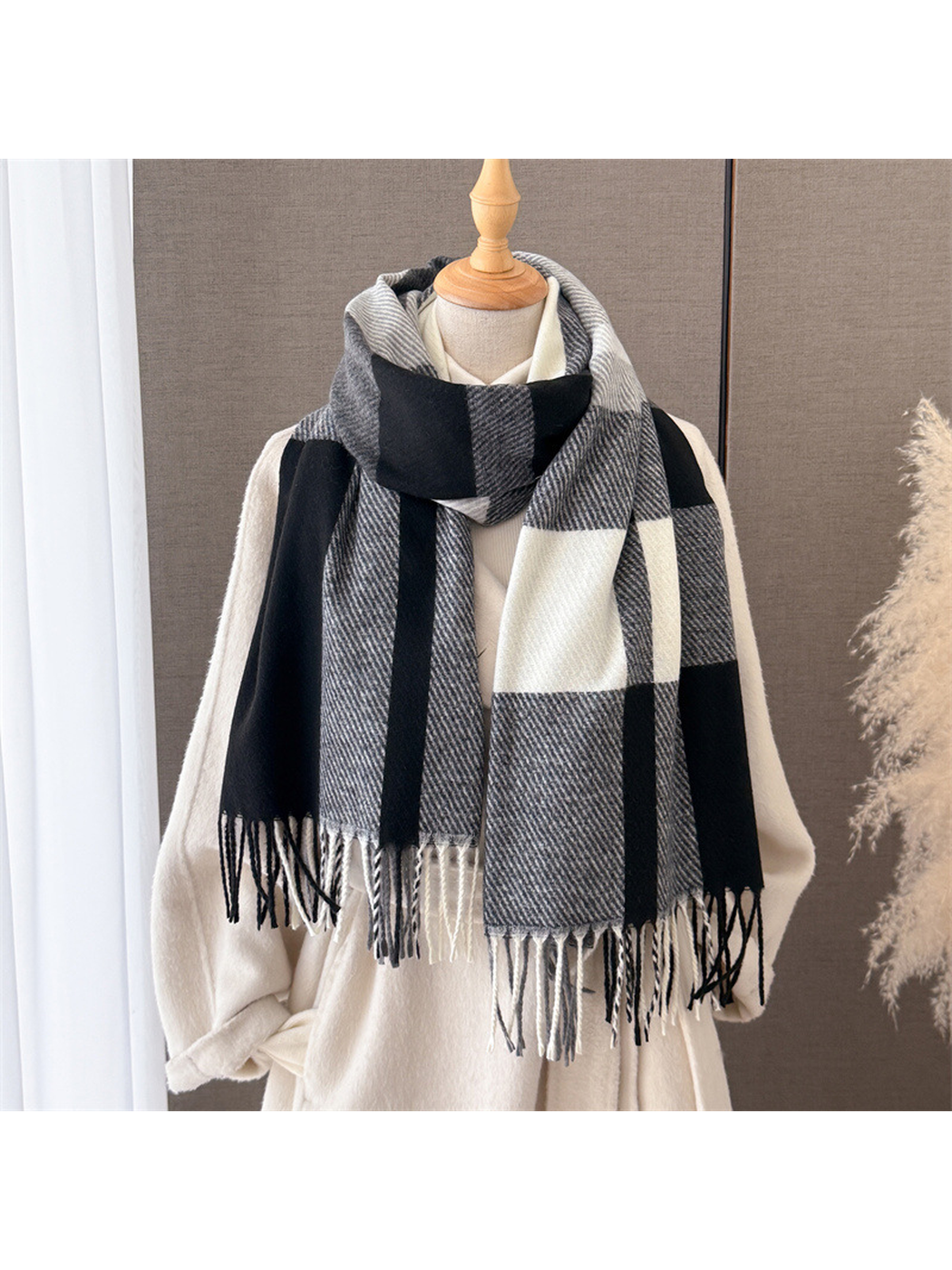 Black, gray and ivory plaid scarf with fringe styled on a cream mannequin