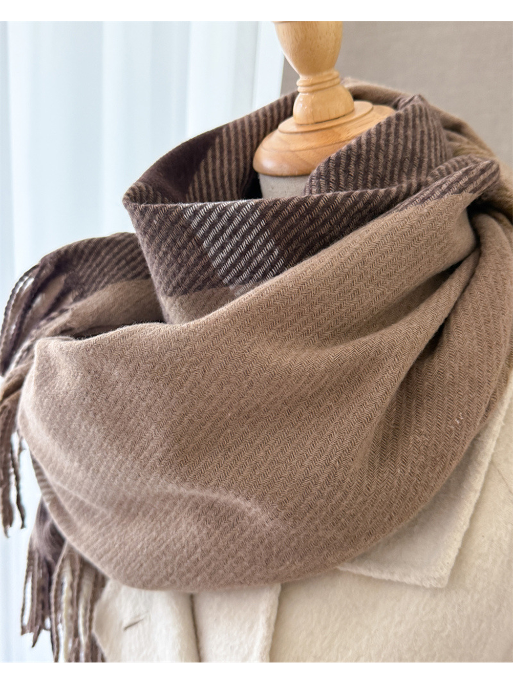 Close-up of the brown plaid scarf's herringbone weave and folded drape