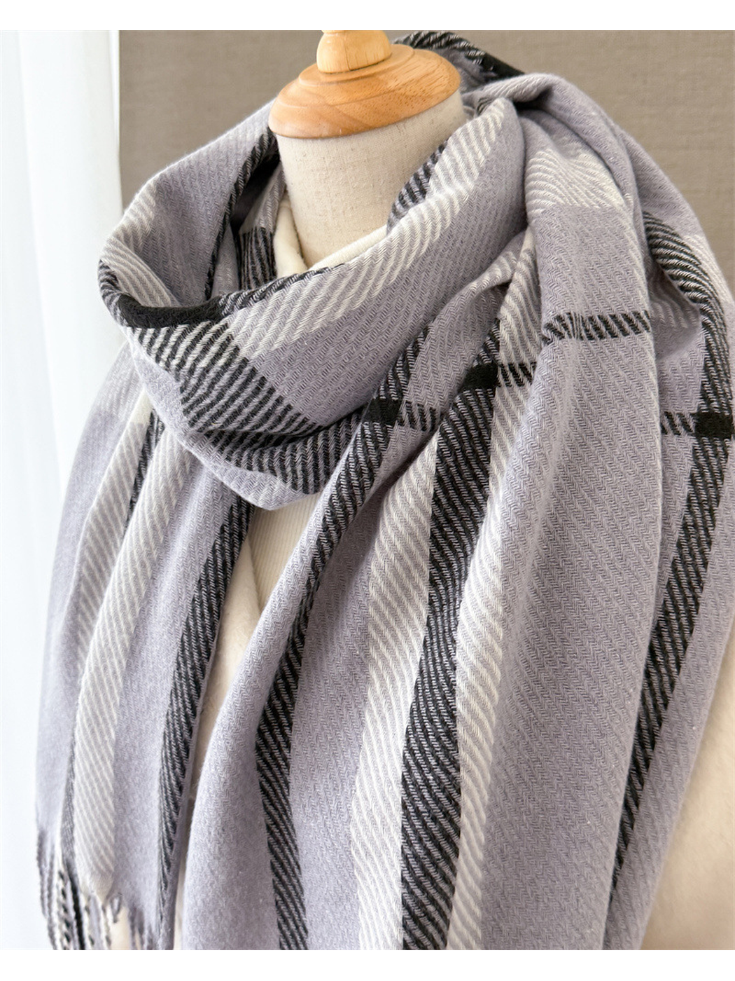 Close-up of the light gray scarf's draped plaid pattern and woven texture