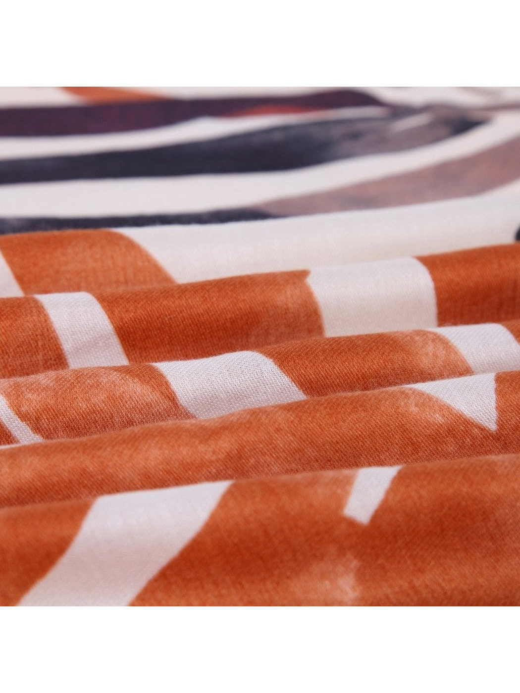 Close-up of the orange and ivory printed scarf gathered in soft folds