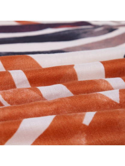 Close-up of the orange and ivory printed scarf gathered in soft folds