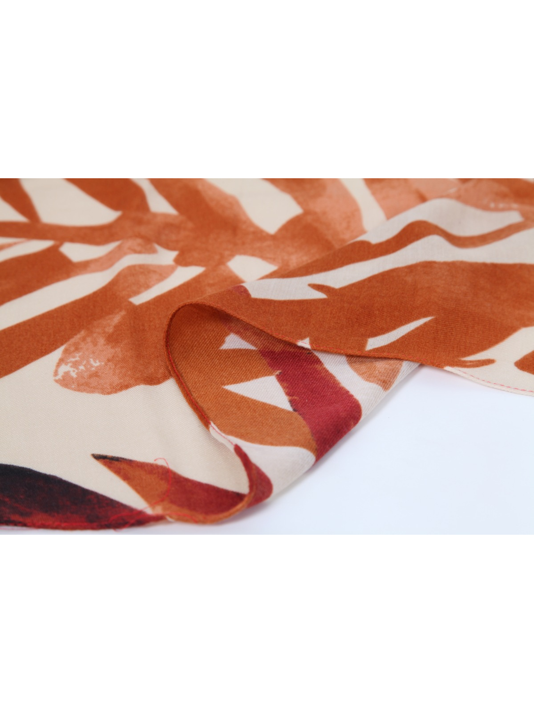 Close-up of the narrow stitched edge on the orange printed scarf