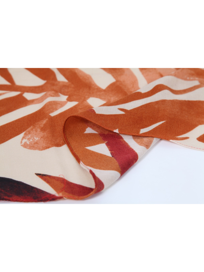 Close-up of the narrow stitched edge on the orange printed scarf