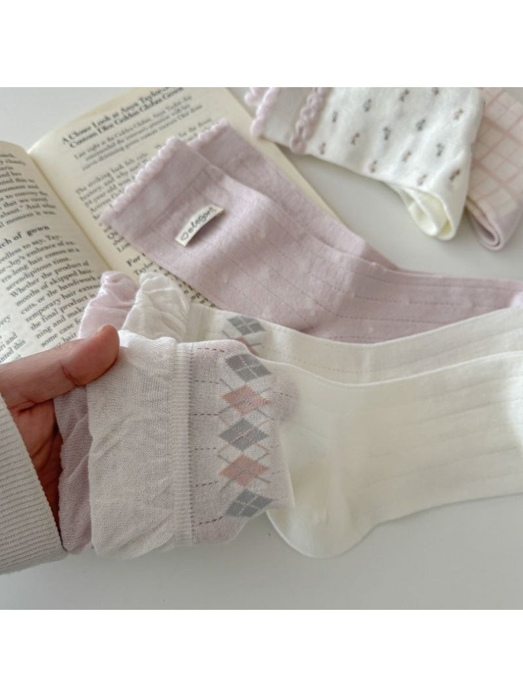 Close-up of ivory argyle, pink pointelle, and striped cuff sock designs