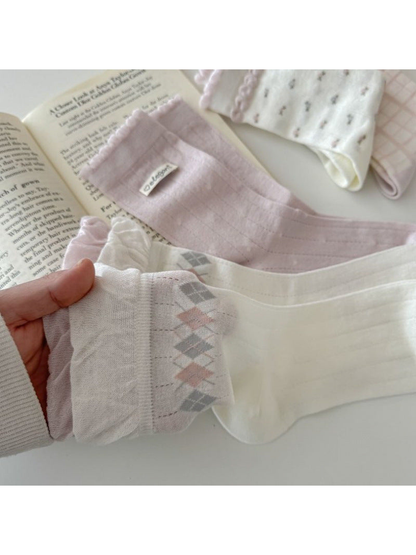 Close-up of ivory argyle, pink pointelle, and striped cuff sock designs
