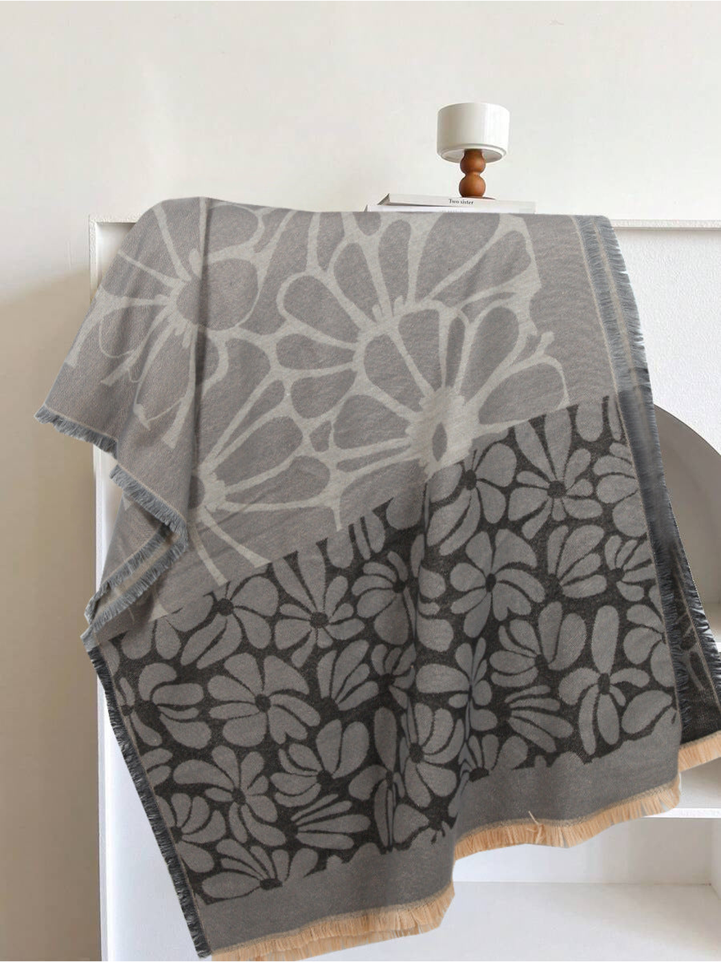 Black and gray floral scarf draped to show its contrasting flower panels and fringe