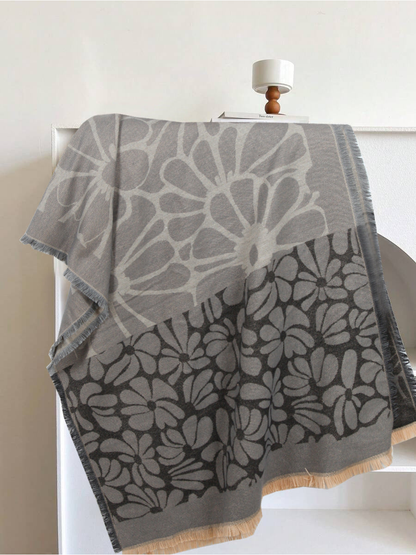 Black and gray floral scarf draped to show its contrasting flower panels and fringe